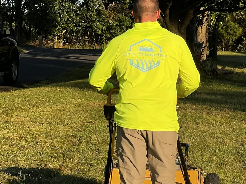 Jimmy Terry running the core aerator across a shaded front lawn