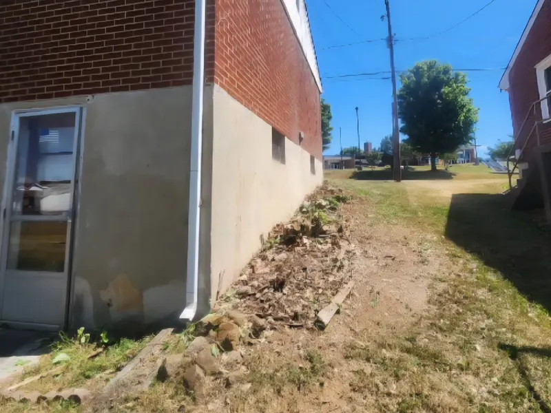 Cleared wall with pulled vines stacked along the foundation in Vinton, VA
