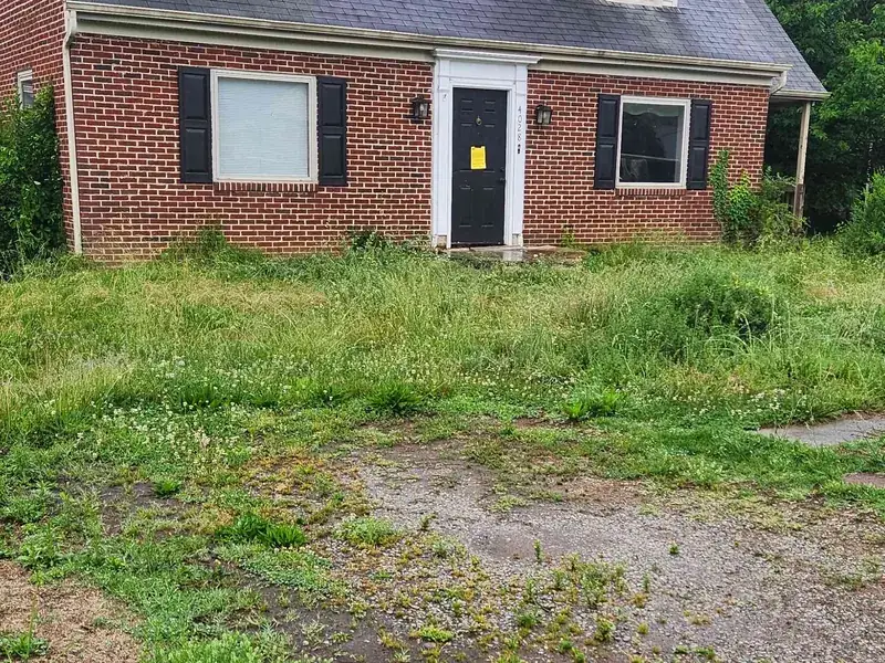 Vacant property overgrown to knee height before cleanup in Vinton, VA